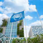 Modern building with UN flag in front under a blue sky with clouds