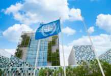 Modern building with UN flag in front under a blue sky with clouds