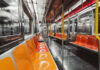 Interior of an empty subway train with orange seats and metallic surfaces