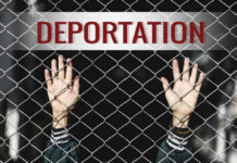 Hands reaching through a metal fence with the word DEPORTATION above