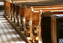 Interior of a church featuring wooden pews and natural light streaming in