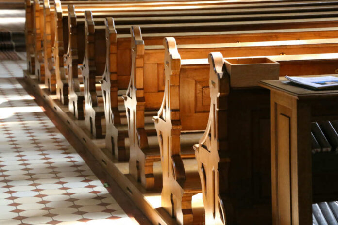 Interior of a church featuring wooden pews and natural light streaming in
