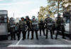 Law enforcement officers in riot gear standing in formation