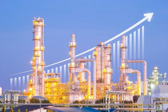 shutterstock_2180795391.jpg Illuminated industrial oil refinery with a growth graph overlay
