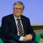 A man in a suit sitting on a green chair during a conference
