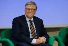 A man in a suit sitting on a green chair during a conference