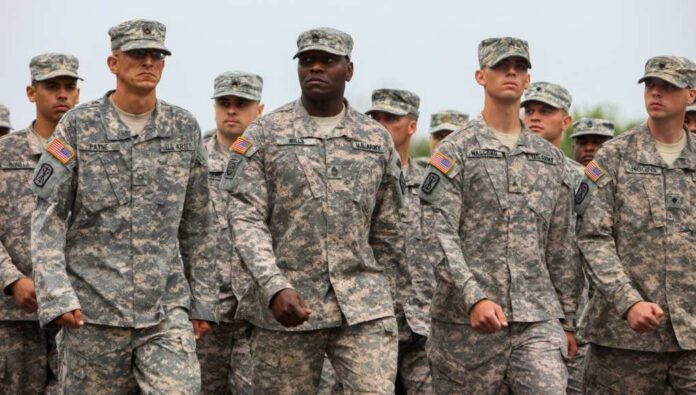 A group of U.S. Army soldiers marching in formation with serious expressions