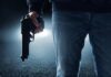 A person holding a handgun in a dark environment