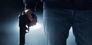 A person holding a handgun in a dark environment