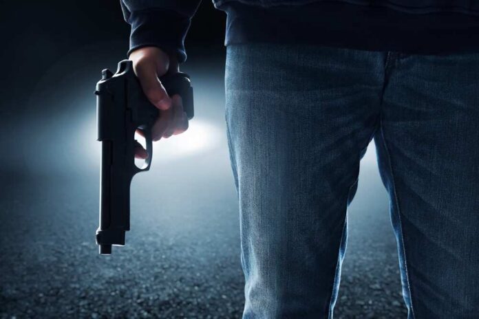 A person holding a handgun in a dark environment