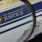 MASS Firings Rock Justice Department Close-up view of the U.S. Department of Justice website through a magnifying glass