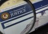 Close-up view of the U.S. Department of Justice website through a magnifying glass