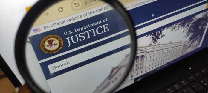 shutterstock_2579491759.jpg Close-up view of the U.S. Department of Justice website through a magnifying glass