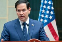 Marco Rubio speaking at a podium with an American flag in the background