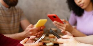 Group of friends sitting at a table, each using their smartphones