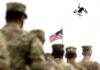 Fallen Soldiers Honored: Middle East War Rages Military personnel standing in formation with a drone flying overhead and an American flag in the background
