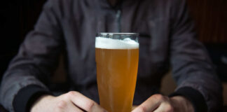 Person holding a glass of craft beer in a bar