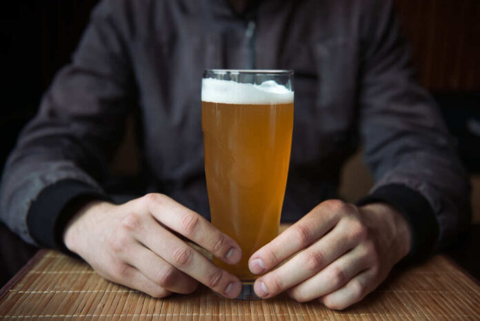 Person holding a glass of craft beer in a bar
