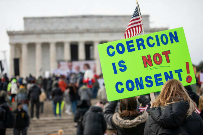 shutterstock2111578241jpg A crowd at a protest with a sign reading COERCION IS NOT CONSENT! in front of the Lincoln Memorial