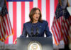 Harris’ Tweet Backlash — Patriotic Optics Fail A female political leader speaking at a podium with American flags in the background