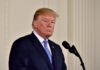 Trump Iran Clash Hijacks Memorial Day A political figure standing at a microphone with a serious expression