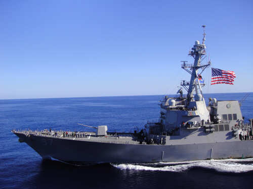 shutterstock_1133692649.jpg A naval destroyer sailing in the ocean with an American flag