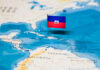 A small flag of Haiti pinned on a map of the Caribbean Sea