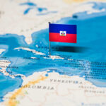 A small flag of Haiti pinned on a map of the Caribbean Sea