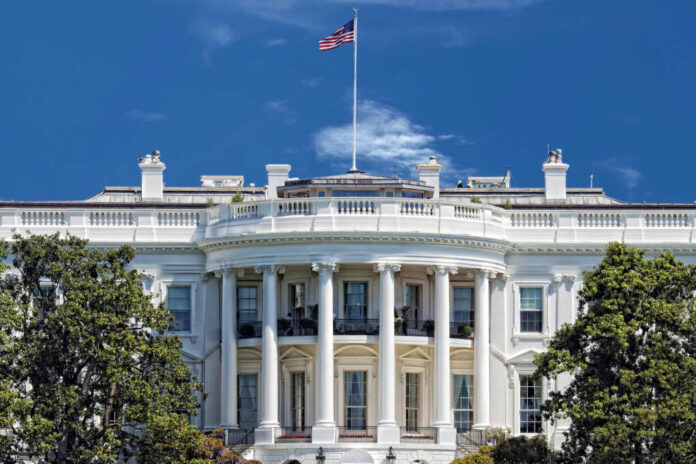 shutterstock_184005656 The White House with an American flag flying against a blue sky