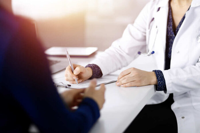 A doctor writing notes during a consultation with a patient