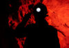Silhouette of a miner wearing a headlamp against a red rocky background