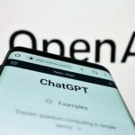 Close-up of a smartphone displaying the ChatGPT interface with the OpenAI logo in the background