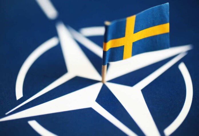 Small Swedish flag on a NATO emblem background