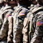 Line of soldiers in military uniforms with American flag patches