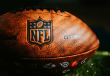 NFL Star’s Fraud: $110M Restitution Demanded Close-up of an official NFL football with team logos and leather texture
