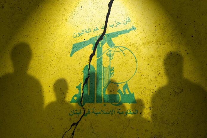 Flag,Of,Terrorist,Organization,Hezbollah,Painted,On,The,Concrete,Wall Silhouettes of two figures against a yellow background featuring Hezbollah's emblem