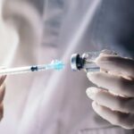 A healthcare professional preparing a syringe from a vial