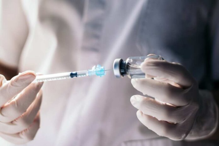 Injecting,Injection,Vaccine,Vaccination,Medicine,Against,Covid-19,Into,A,Syringe. A healthcare professional preparing a syringe from a vial