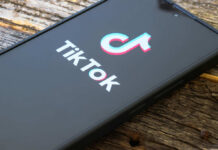 Close-up of a smartphone displaying the TikTok logo on a wooden surface