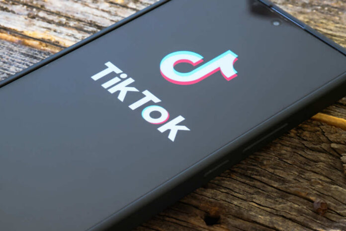 shutterstock_2489941705.jpg Close-up of a smartphone displaying the TikTok logo on a wooden surface