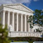 The Supreme Court building with columns and a statue in front