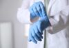 Unsolved Amnesia Mystery: Drive Wipe Raises Suspicions A medical professional putting on blue gloves in a clinical setting