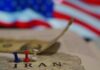 Map of Iran with push pins and a dollar bill in front of an American flag