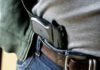Democratic Aide’s Gun Charges Vanish Mysteriously A handgun partially visible in a belt holster worn by a person in casual clothing