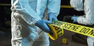 Forensic investigators in protective suits setting up crime scene tape