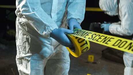 Forensic investigators in protective suits setting up crime scene tape