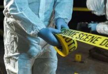 Forensic investigators in protective suits setting up crime scene tape