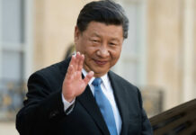 Axis Tightens: Xi Heads To Pyongyang A political leader in formal attire smiling and waving