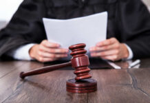 Judge Slams Illinois’ Speech Crackdown A judge holding documents with a gavel in the foreground
