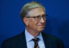 A business leader with glasses smiling in front of a blue background